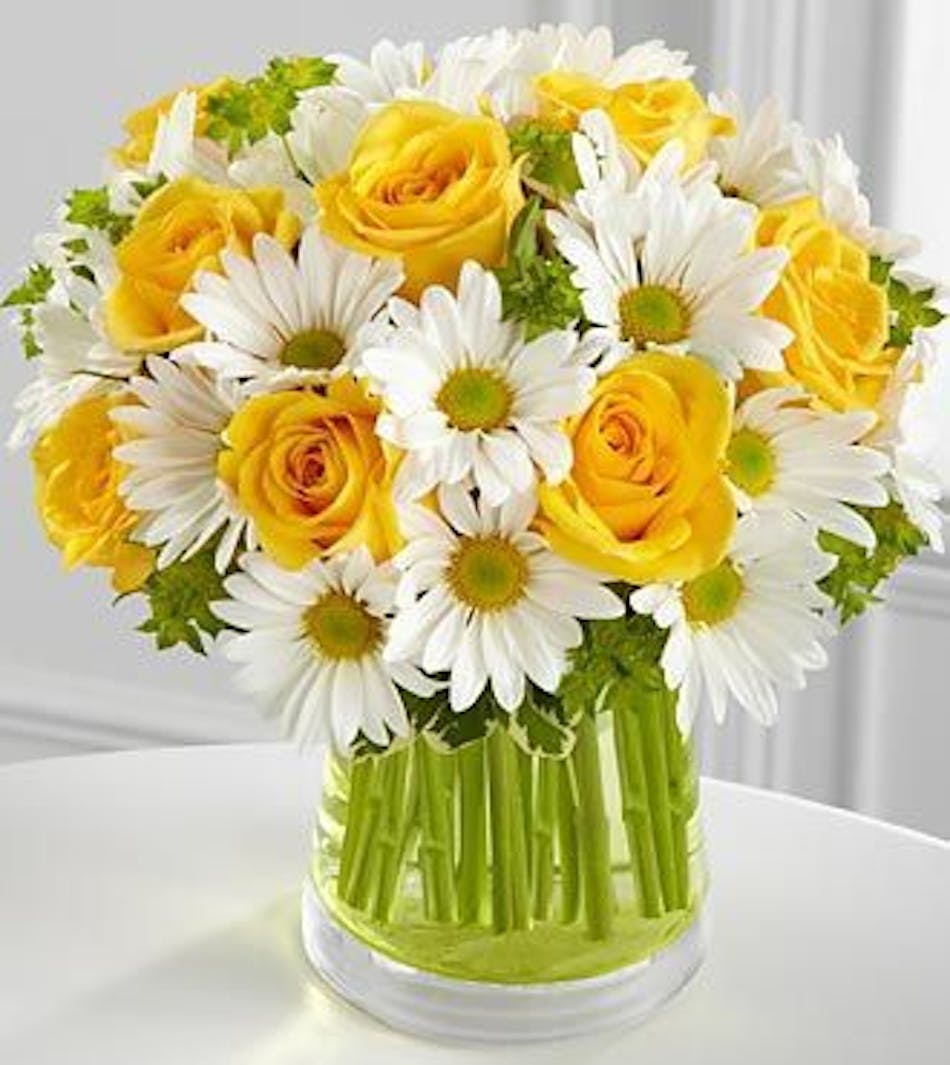 Yellow and white flowers in a clear glass vase.